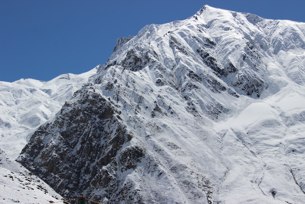 a large mountain covered in snow under a blue sky