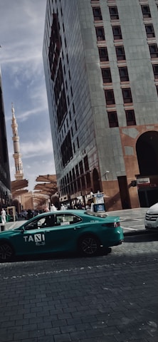 A scenic view of a taxi driving through Jeddah city streets at sunset.