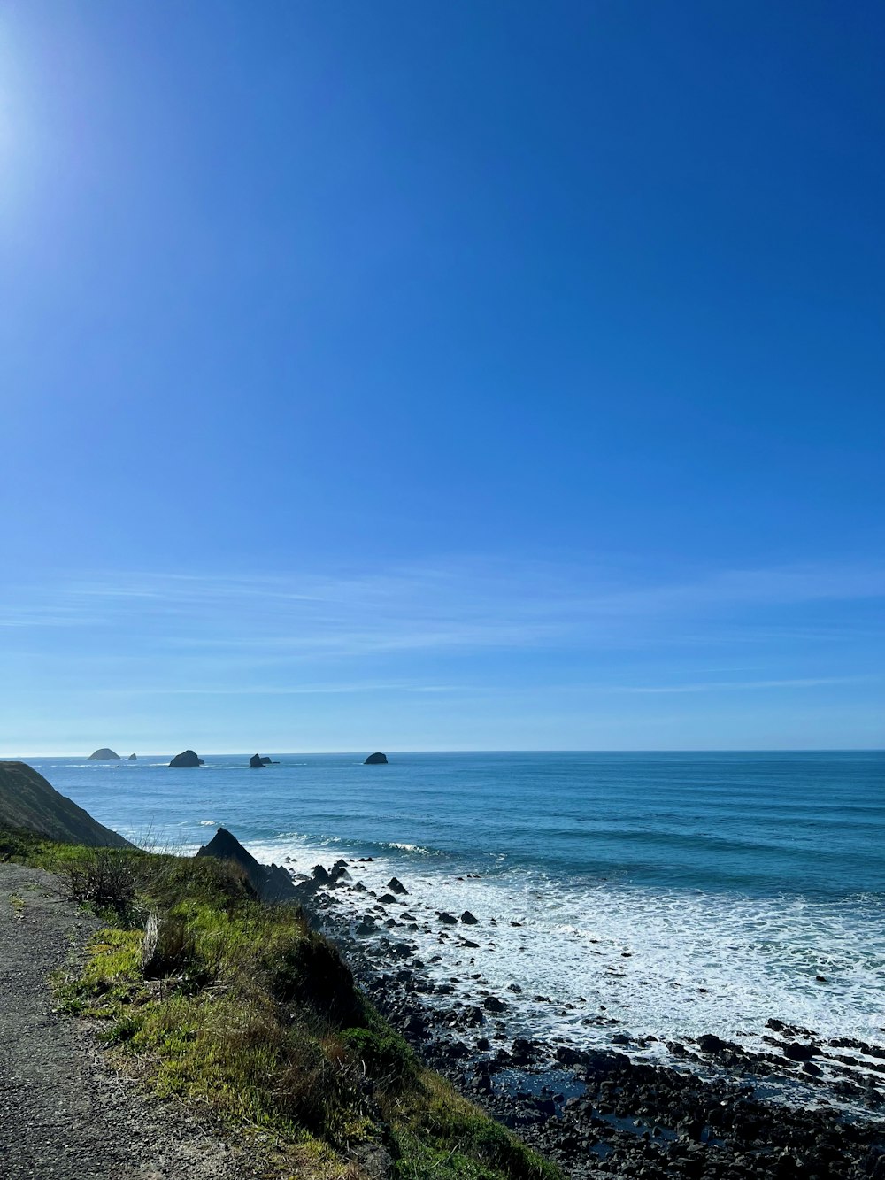 a view of the ocean from the side of a road