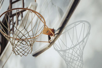 Close-up of a handmade basketball net hanging on an outdoor hoop, sunlight casting warm shadows.