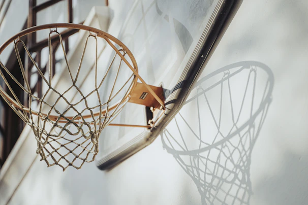 Close-up of a handmade basketball net hanging on an outdoor hoop, sunlight casting warm shadows.