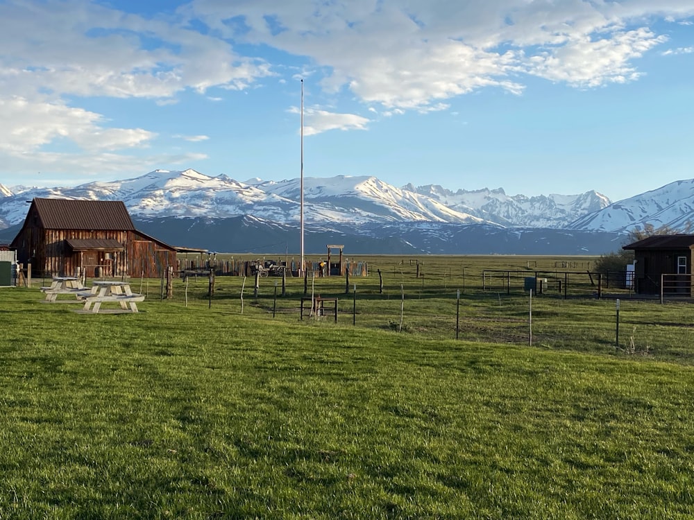 a field with a picnic table and a barn in the background