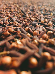Close-up of glossy, dark brown cloves neatly arranged in a wooden crate.