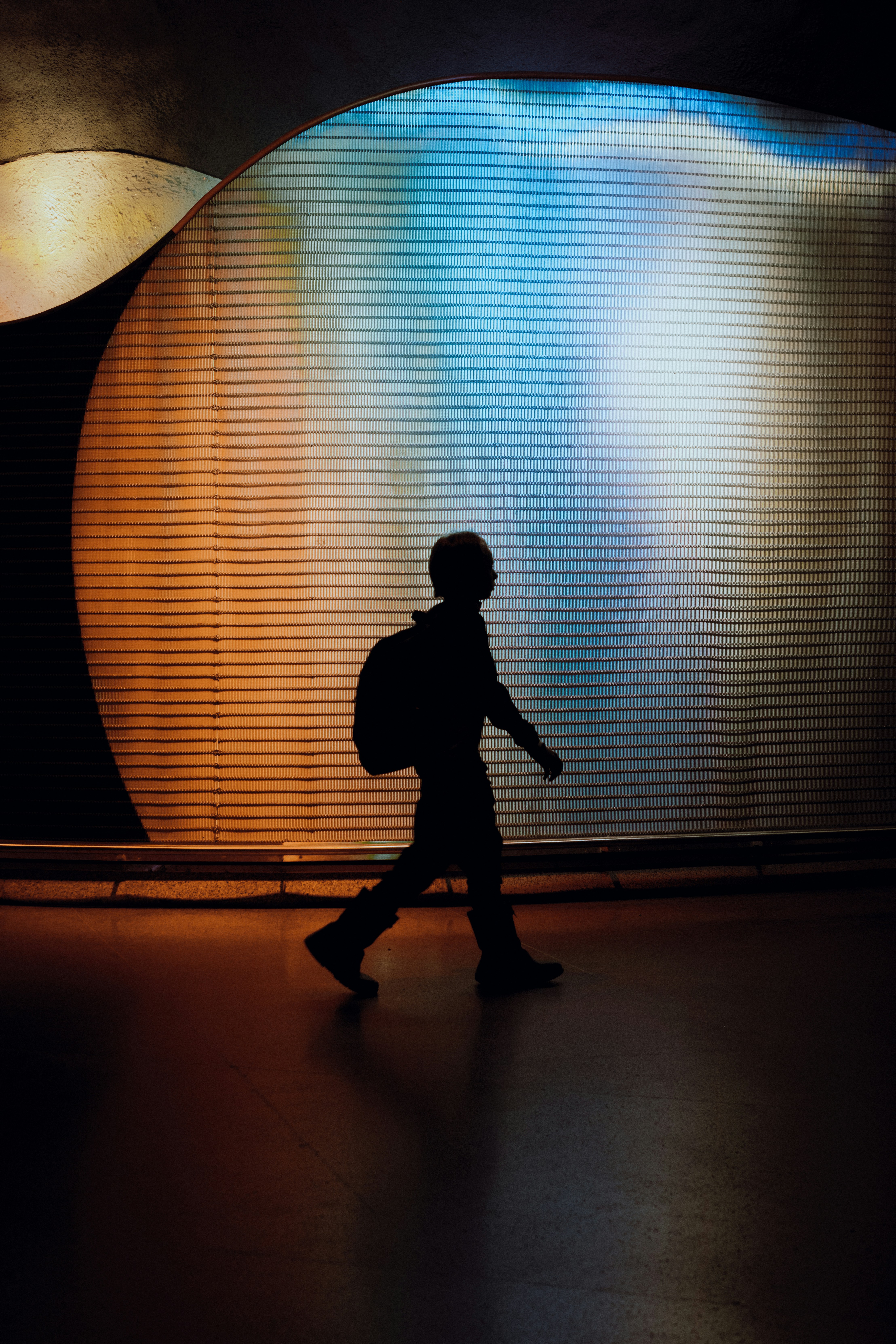 uma silhueta de uma pessoa andando em frente a uma parede