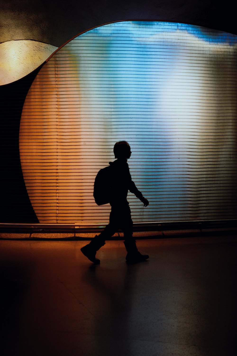 a silhouette of a person walking in front of a wall