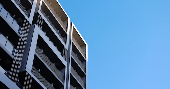 Modern condominium building exterior with clean lines and blue sky background