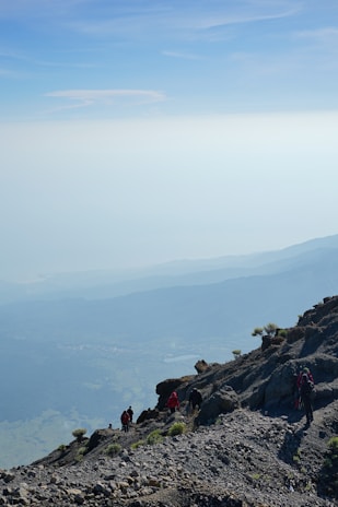 A group hiking up a scenic trail with mountains in the background on a clear day.