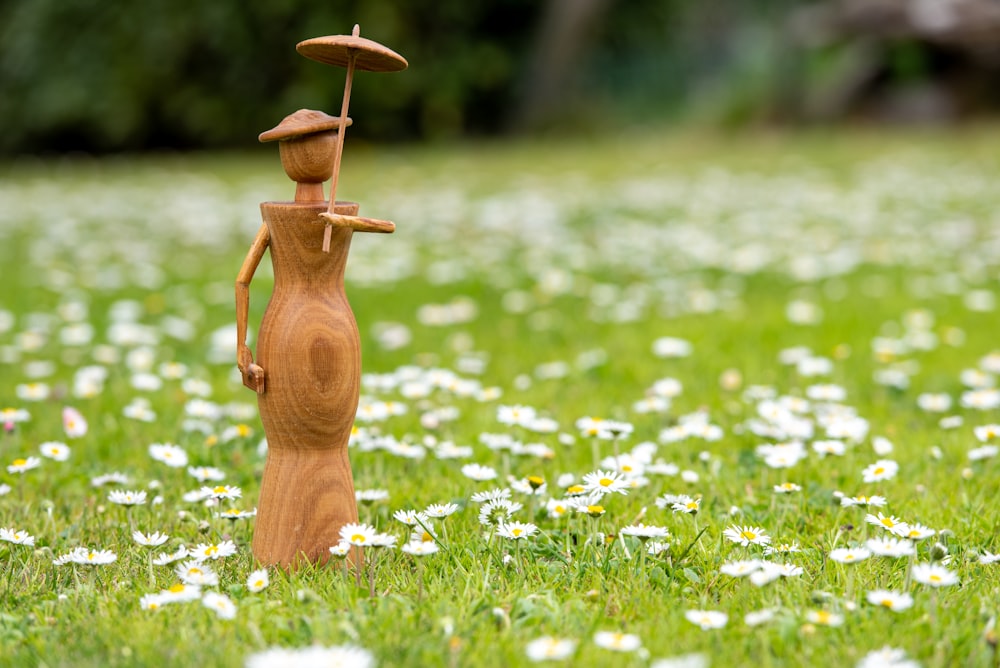 a wooden figure standing in a field of daisies