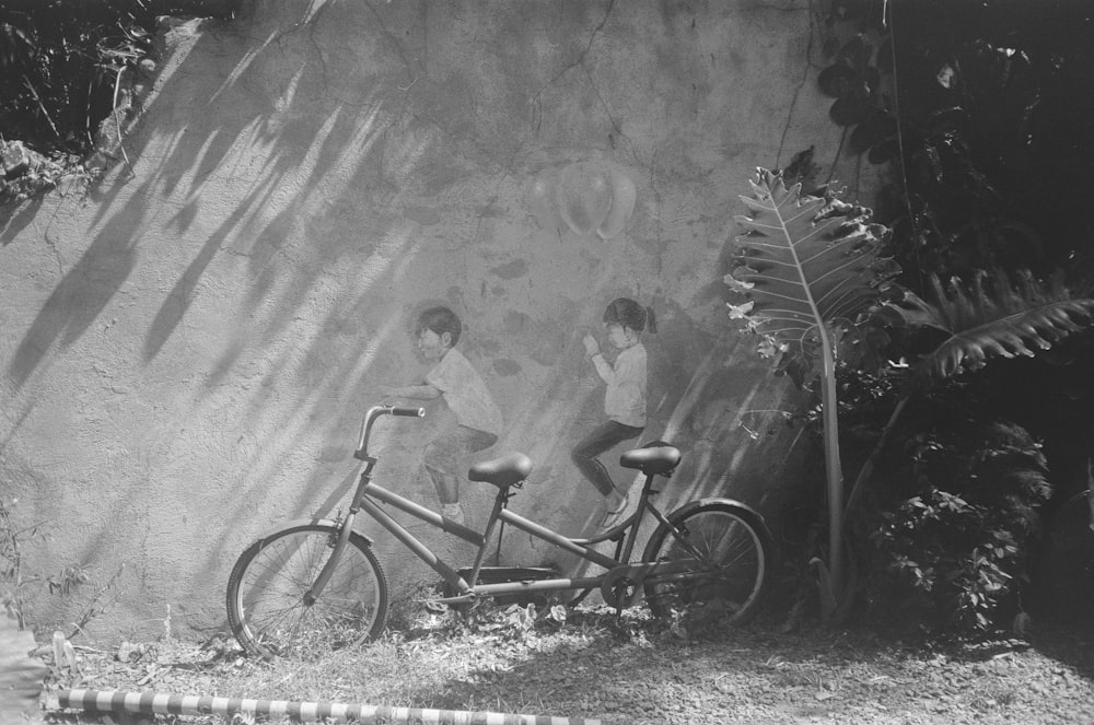 a black and white photo of two boys on a bike