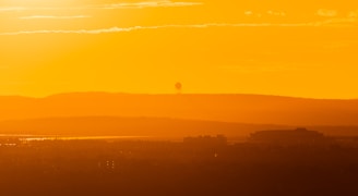 A panoramic view of a seismic survey team deploying equipment across rugged terrain at dawn.