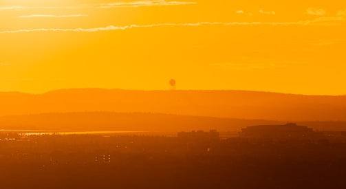 A panoramic view of a seismic survey team deploying equipment across rugged terrain at dawn.