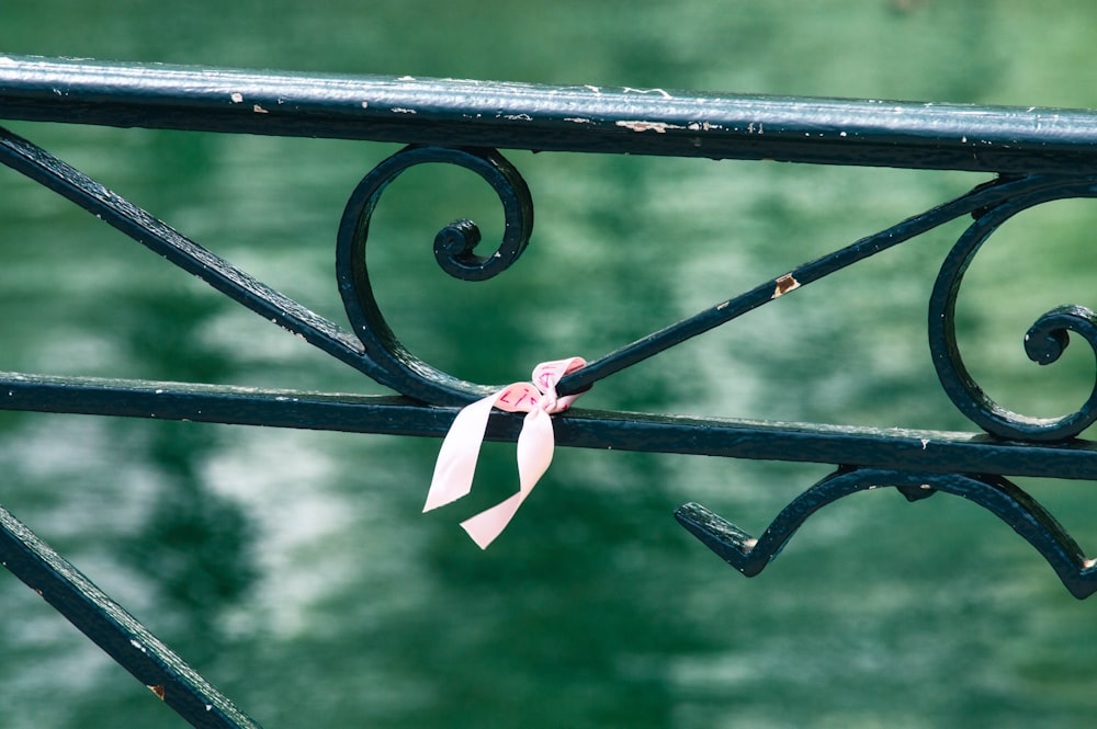 a pink ribbon tied to a wrought iron fence