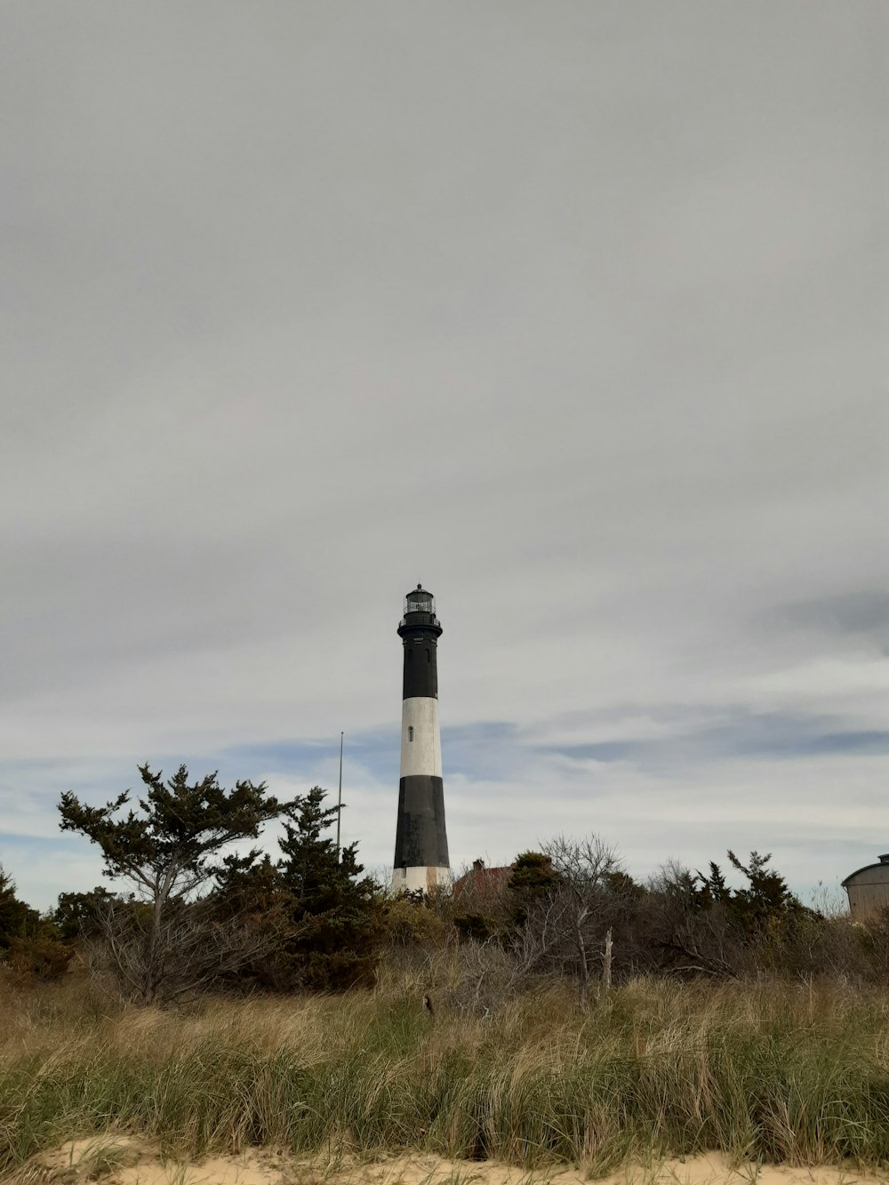 a black and white lighthouse on a cloudy day