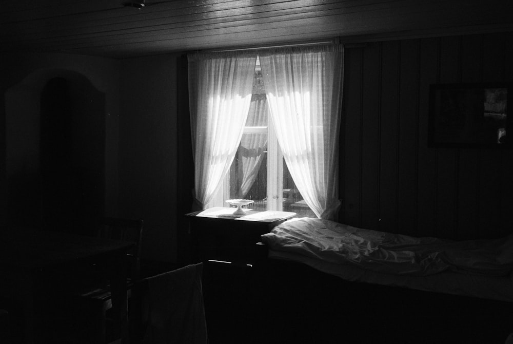 une chambre sombre avec un lit et une fenêtre