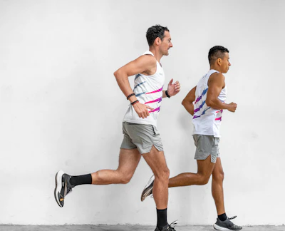 a man running next to another man in a white tank top