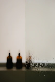 Minimalist composition featuring Lafiyah Detox bottle with water droplets on a reflective black background