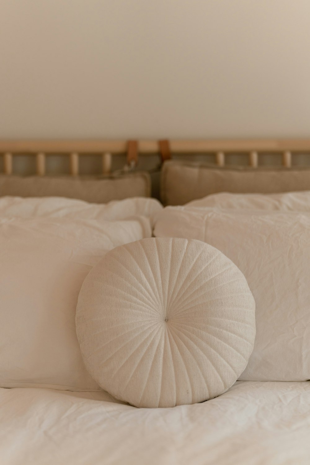a white round pillow on a white bed