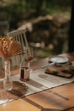 A soft, elegant arrangement of flowers and charcuterie on a wooden board with warm natural lighting.