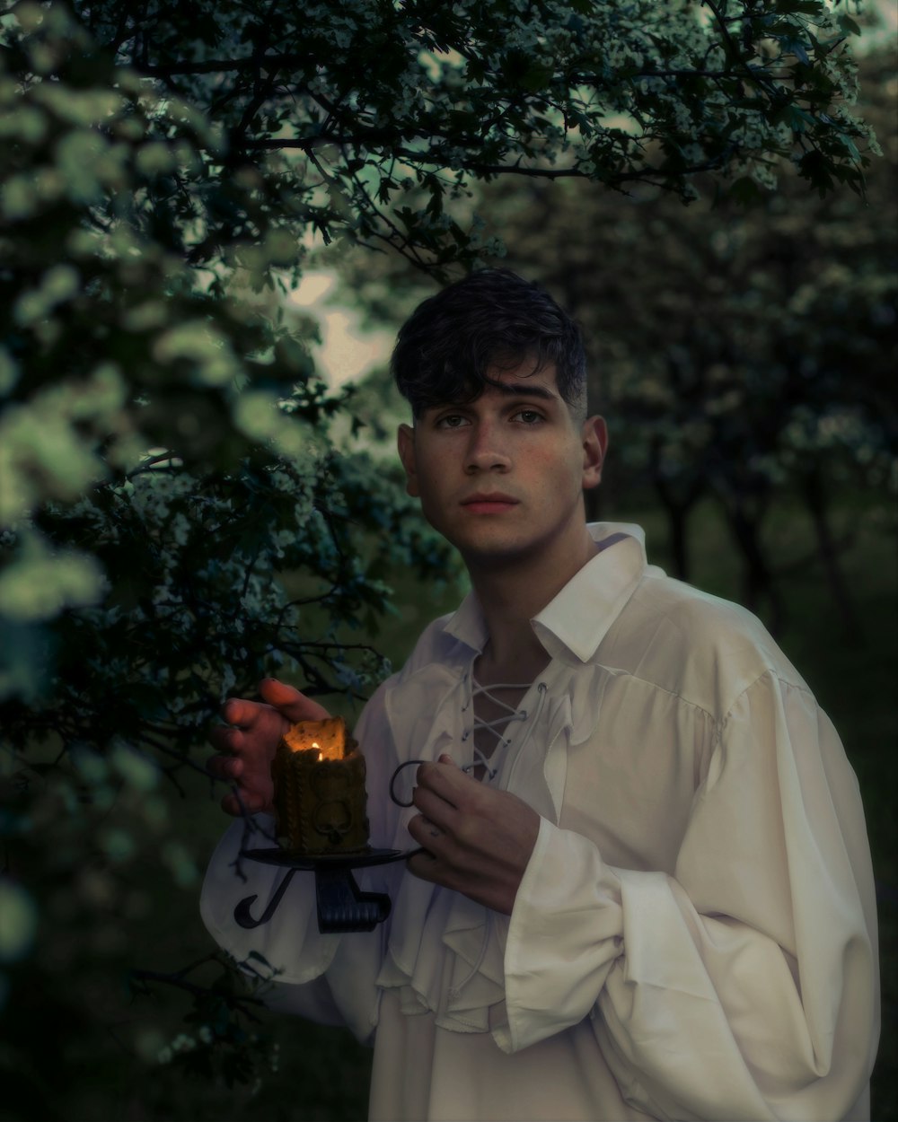 a man in a white shirt holding a lit candle