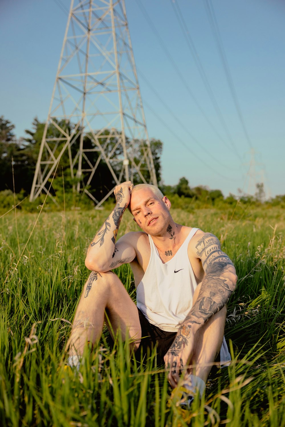 a man with tattoos sitting in the grass