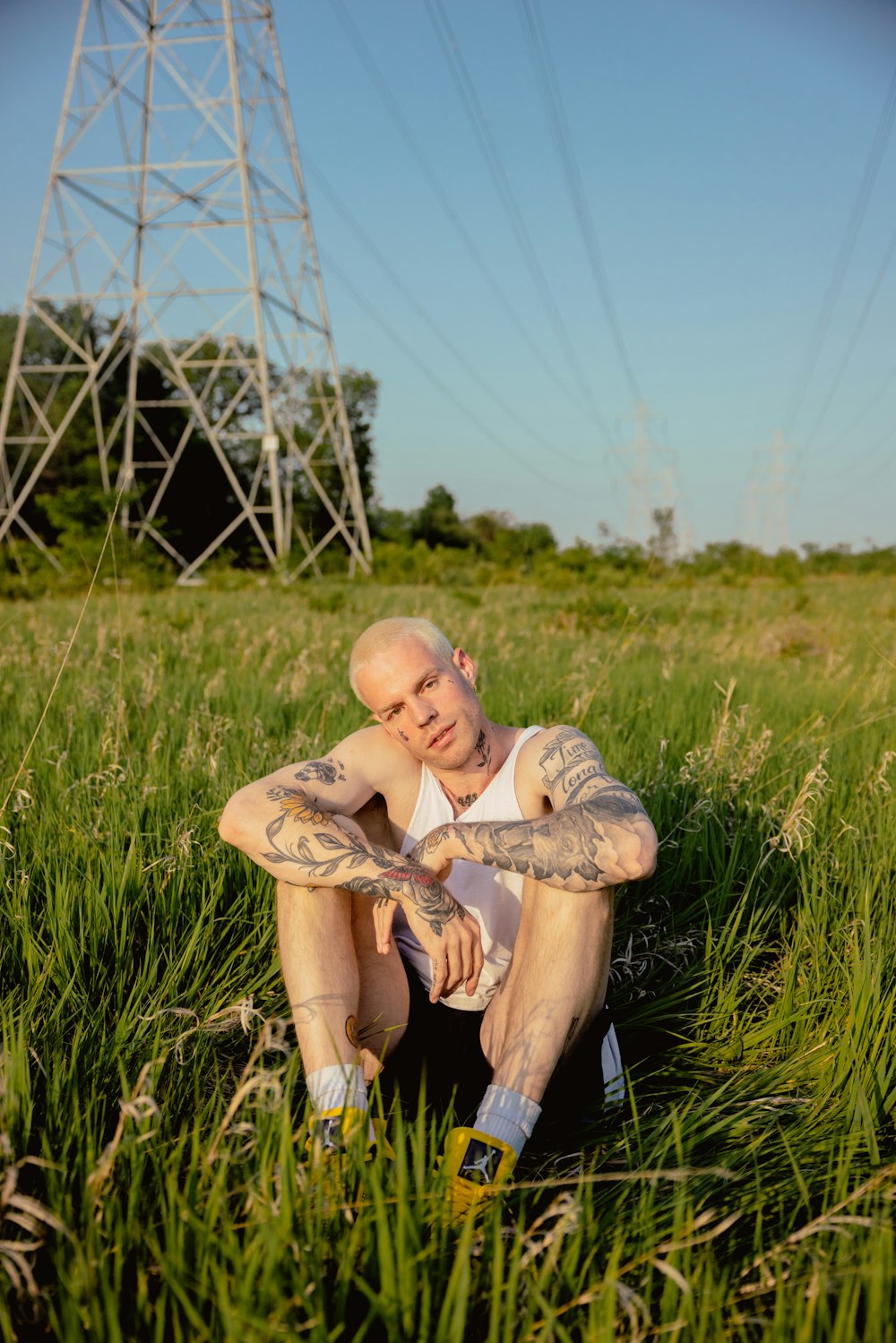 a man with tattoos sitting in a field