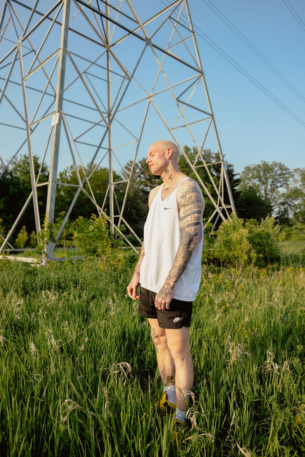 a man with tattoos standing in tall grass