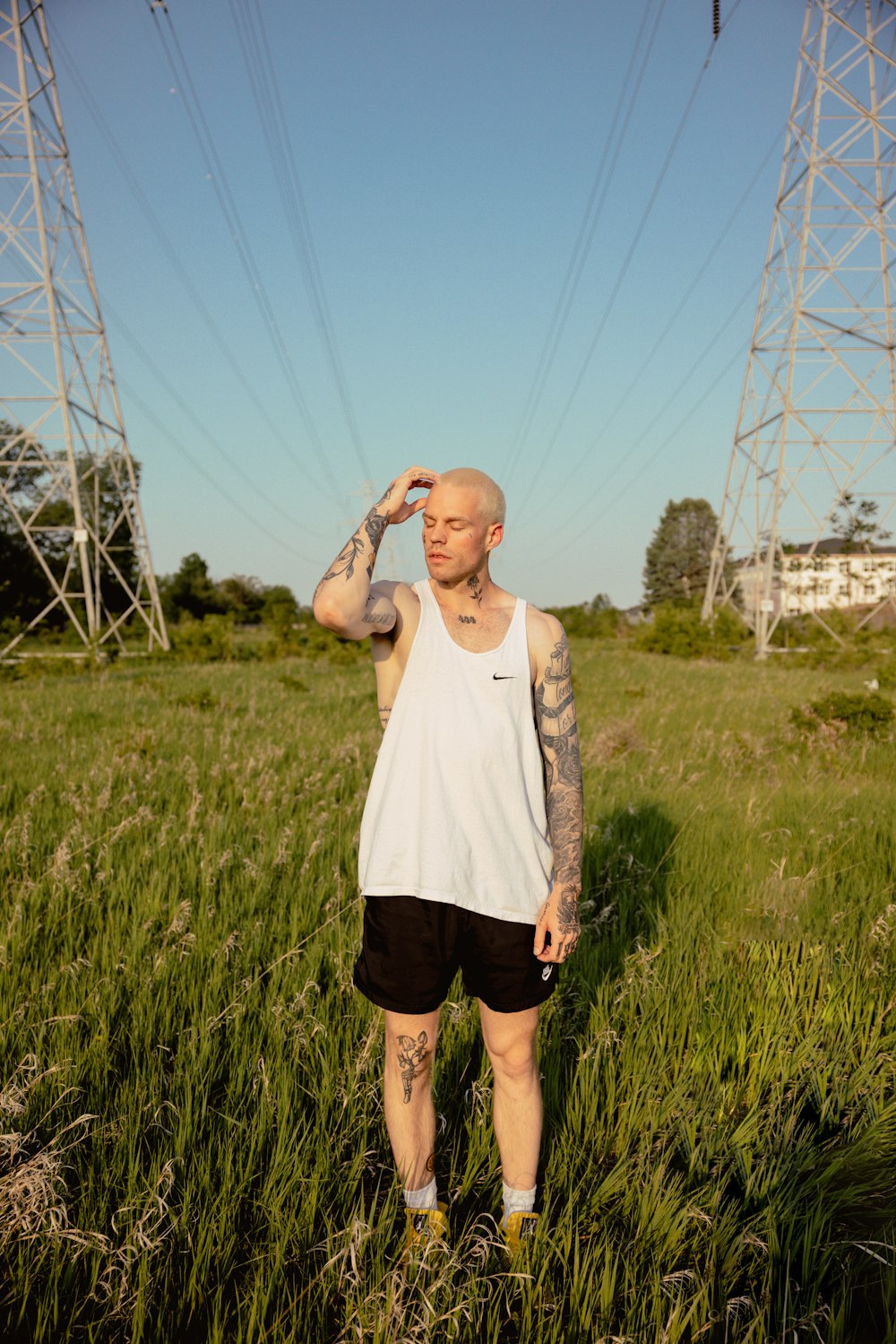 a tattooed man standing in a field of tall grass