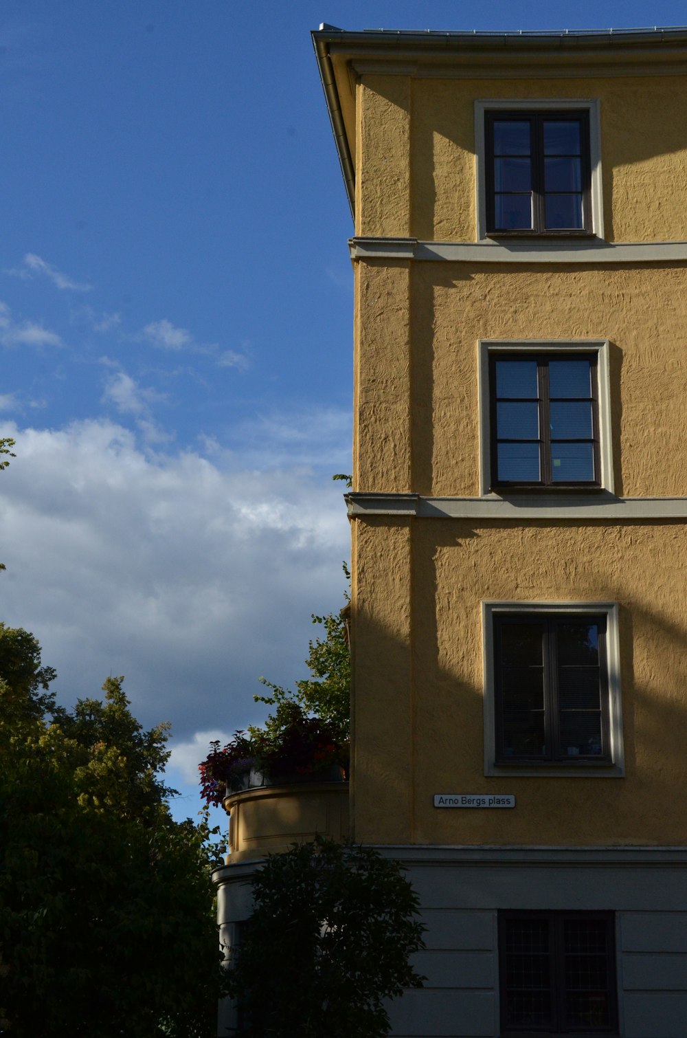 a tall yellow building with a clock on it's side