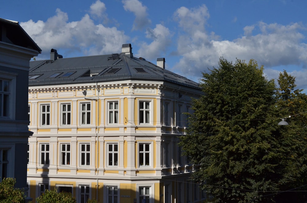 a large yellow and white building next to a tree