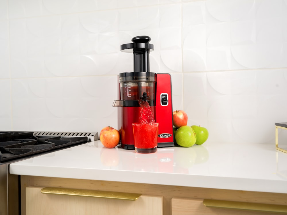 a red juicer sitting on top of a white counter