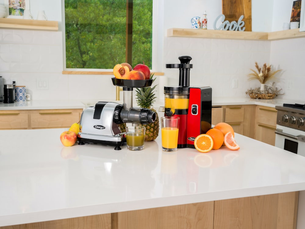 a kitchen counter with a juicer, blender, and oranges on it