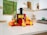 A bright kitchen countertop with a modern juicer and fresh fruits nearby.