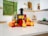 A bright kitchen countertop with a modern juicer and fresh fruits nearby.