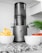 A bright kitchen countertop with a modern juicer and fresh fruits ready for juicing.
