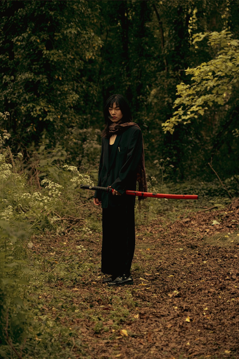 a woman with a sword standing in the woods