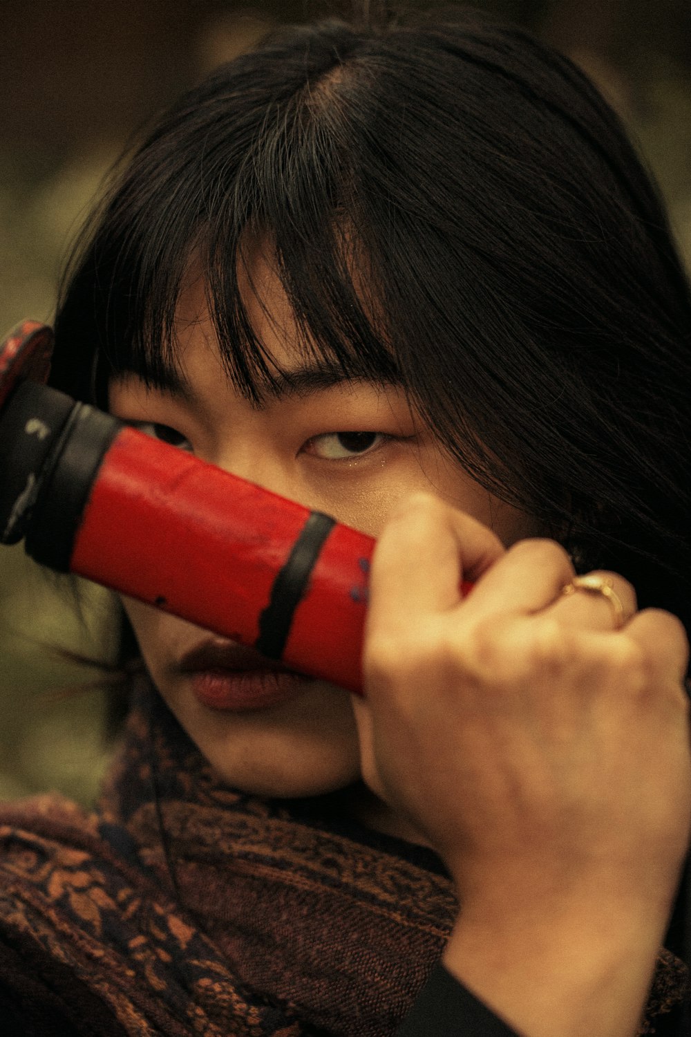 a woman holding a red object up to her face