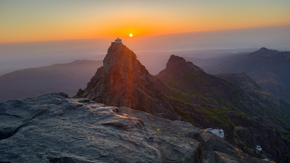 the sun is setting over a mountain peak