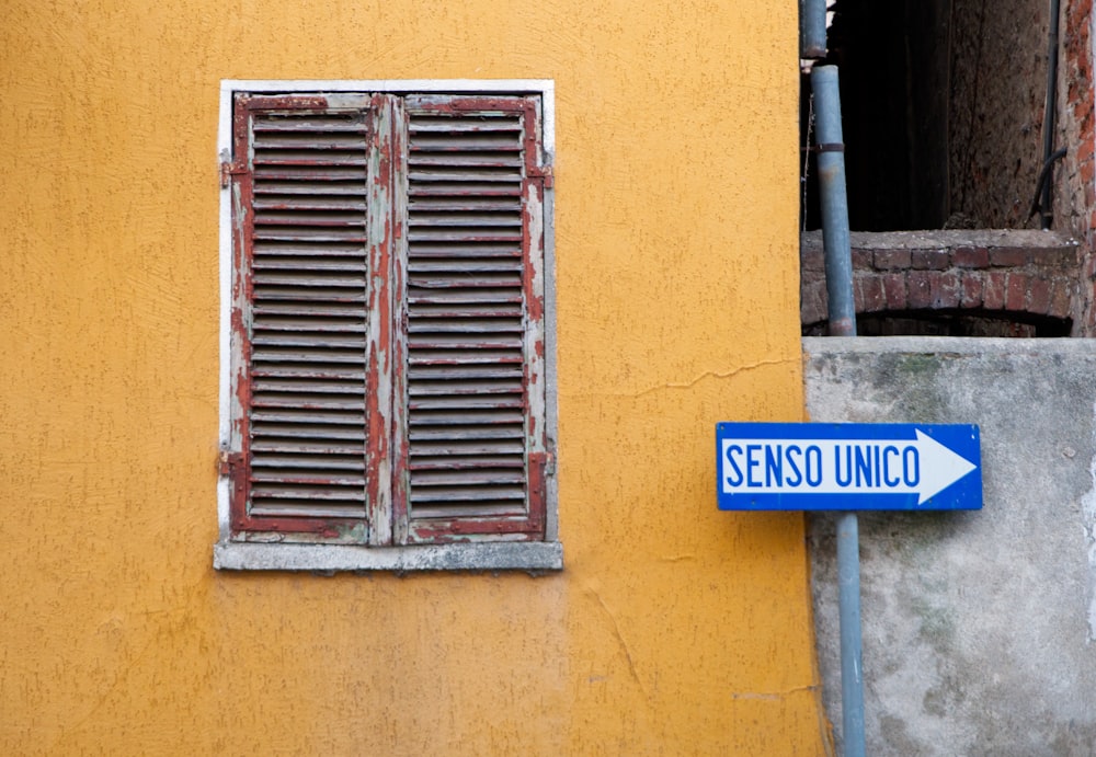 a blue street sign next to a yellow building