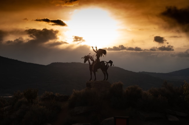 A dramatic sunset silhouette of cavalry charging across open terrain.