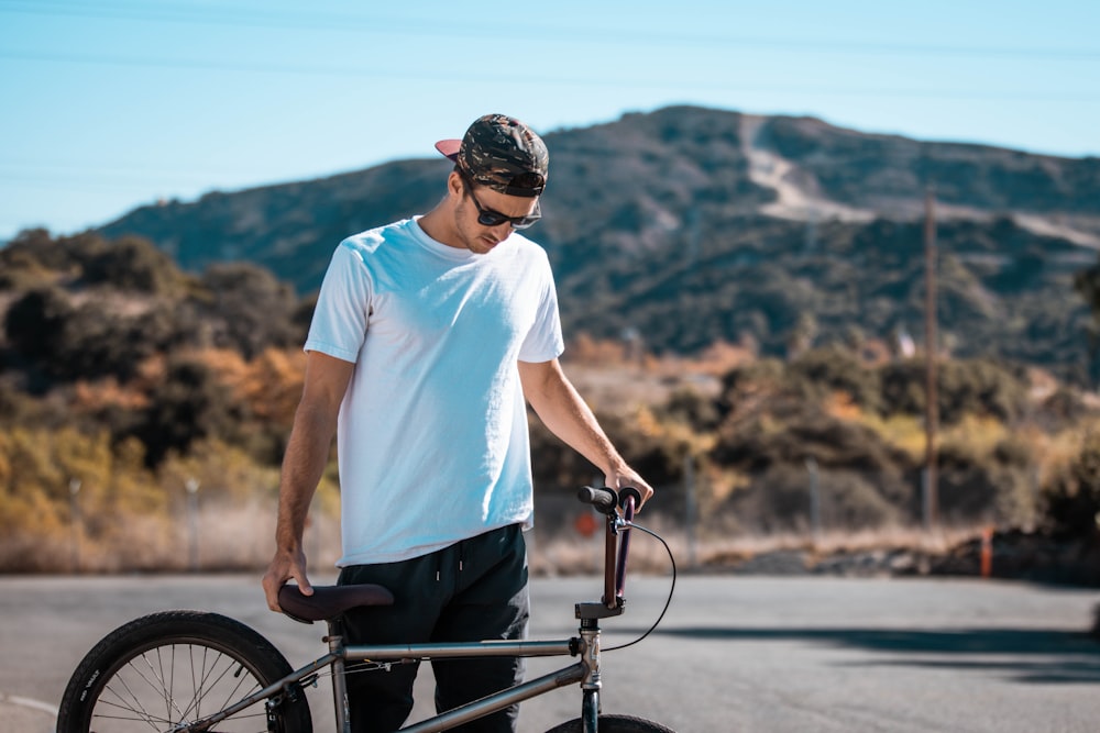 a man holding a bike on the side of the road