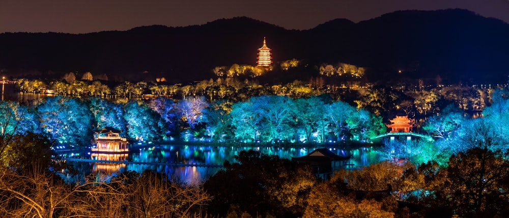 a night view of a city with a lake and trees