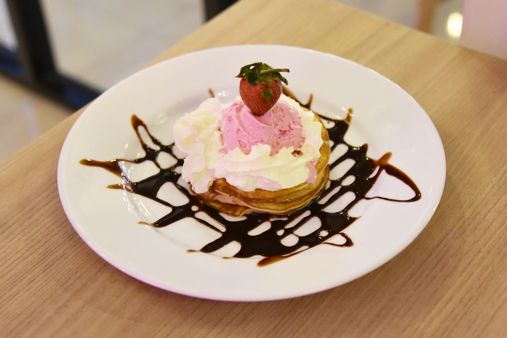 ein weißer Teller mit einem mit Schokolade überzogenen Dessert