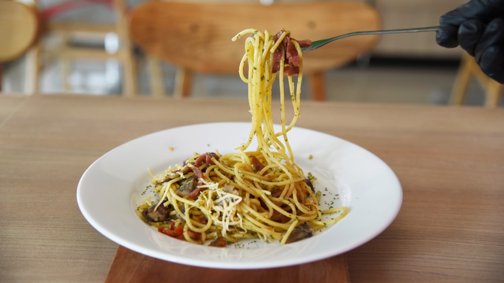 un piatto bianco condito con spaghetti e salsa