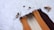 Several hair extensions in varying shades from orange to brown are laid out on a furry white surface. Natural elements like small pine cones and sticks add a rustic touch to the arrangement.