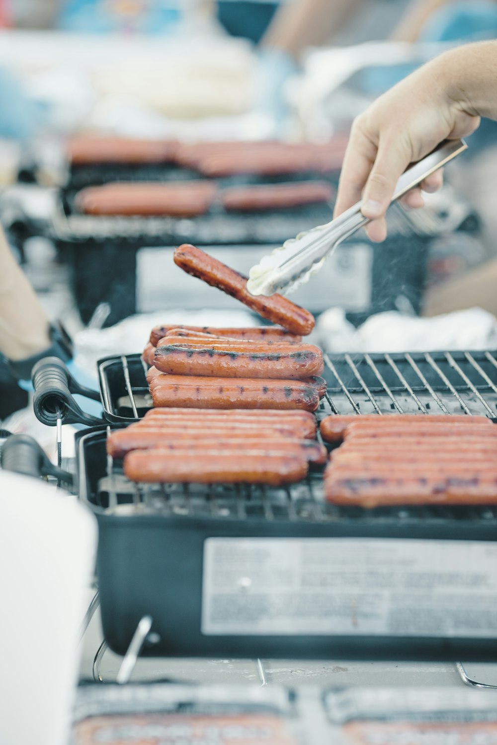 a person cooking hot dogs on a grill