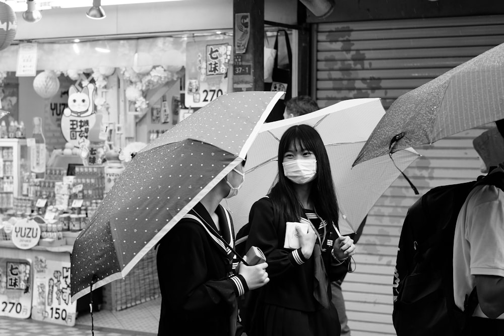 a woman wearing a face mask while holding two umbrellas