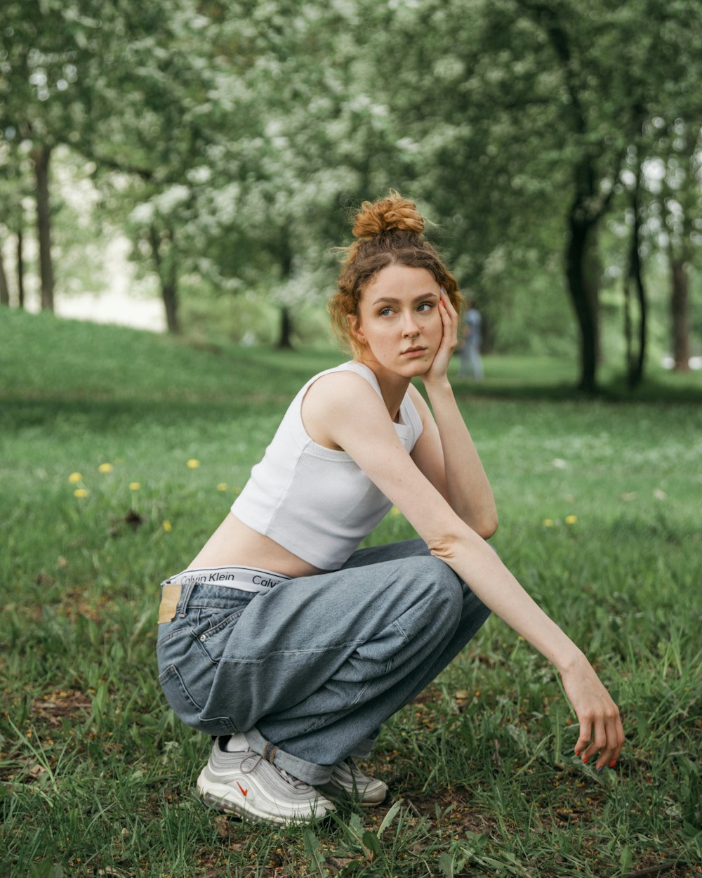 a woman squatting on the grass in a park