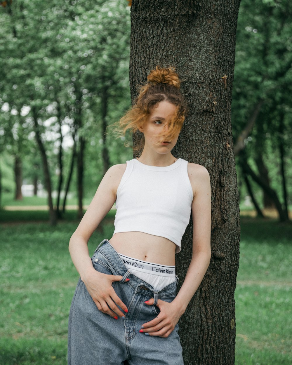 a woman standing next to a tree in a park