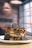 A decadent dessert is served on a white plate, featuring layers of waffles topped with a generous amount of creamy chocolate sauce, drizzles of syrup, and garnished with chocolate sandwich cookies.