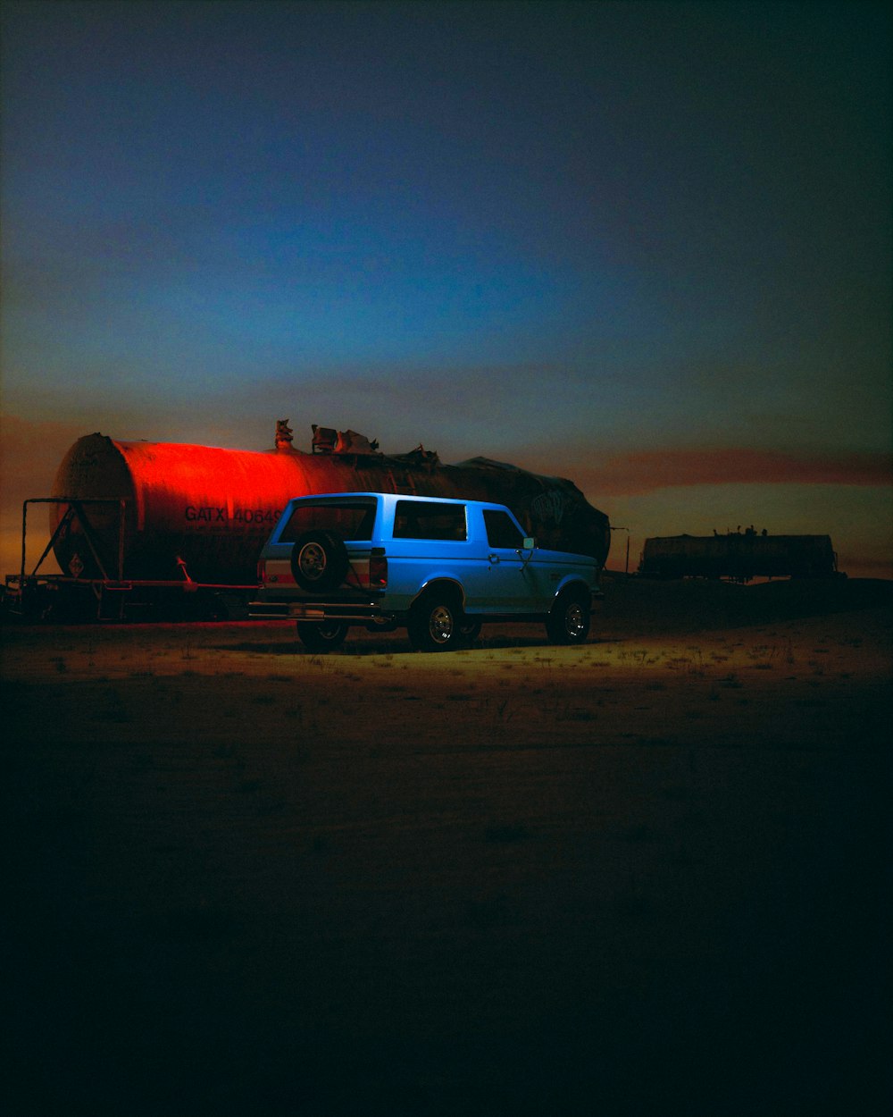 a blue truck parked next to a red tanker